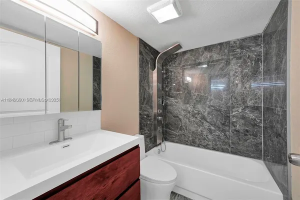 a bathroom with a bathtub shower sink vanity mirror and toilet