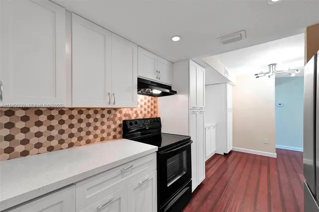 a kitchen with granite countertop a stove and a wooden floor