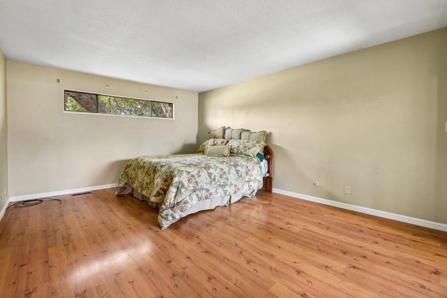 6180 Rustic Hills Drive Rocklin, CA 95677 - Photo 23 of 37 a bedroom with a bed and wooden floor