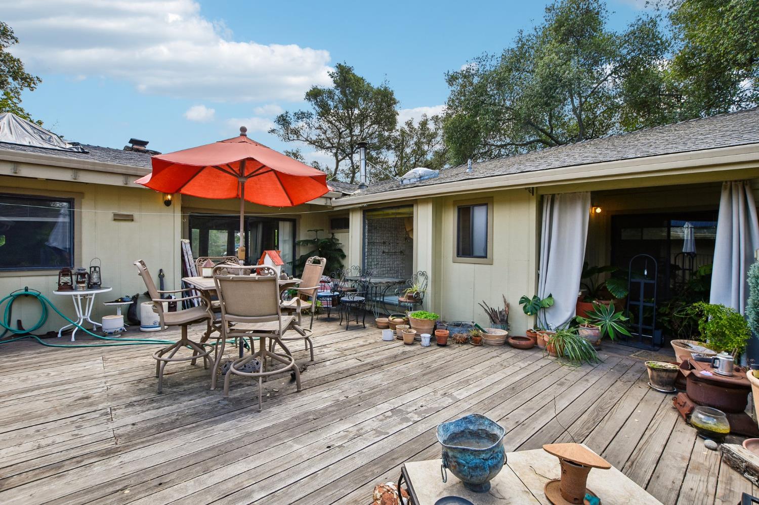 6180 Rustic Hills Drive Rocklin, CA 95677 - Photo 33 of 37 a view of a patio with couches table and chairs under an umbrella with potted plants