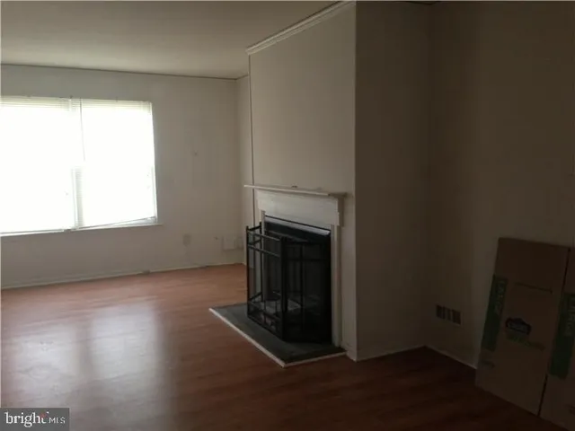 an empty room with wooden floor cabinet and windows