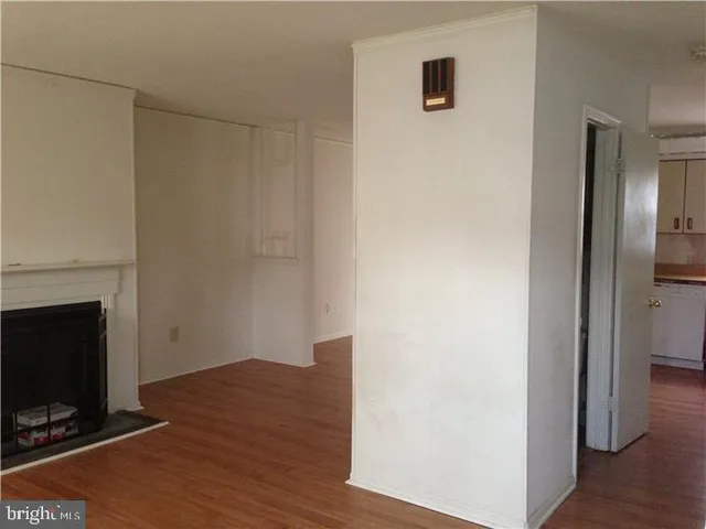a view of a livingroom with wooden floor and a fireplace