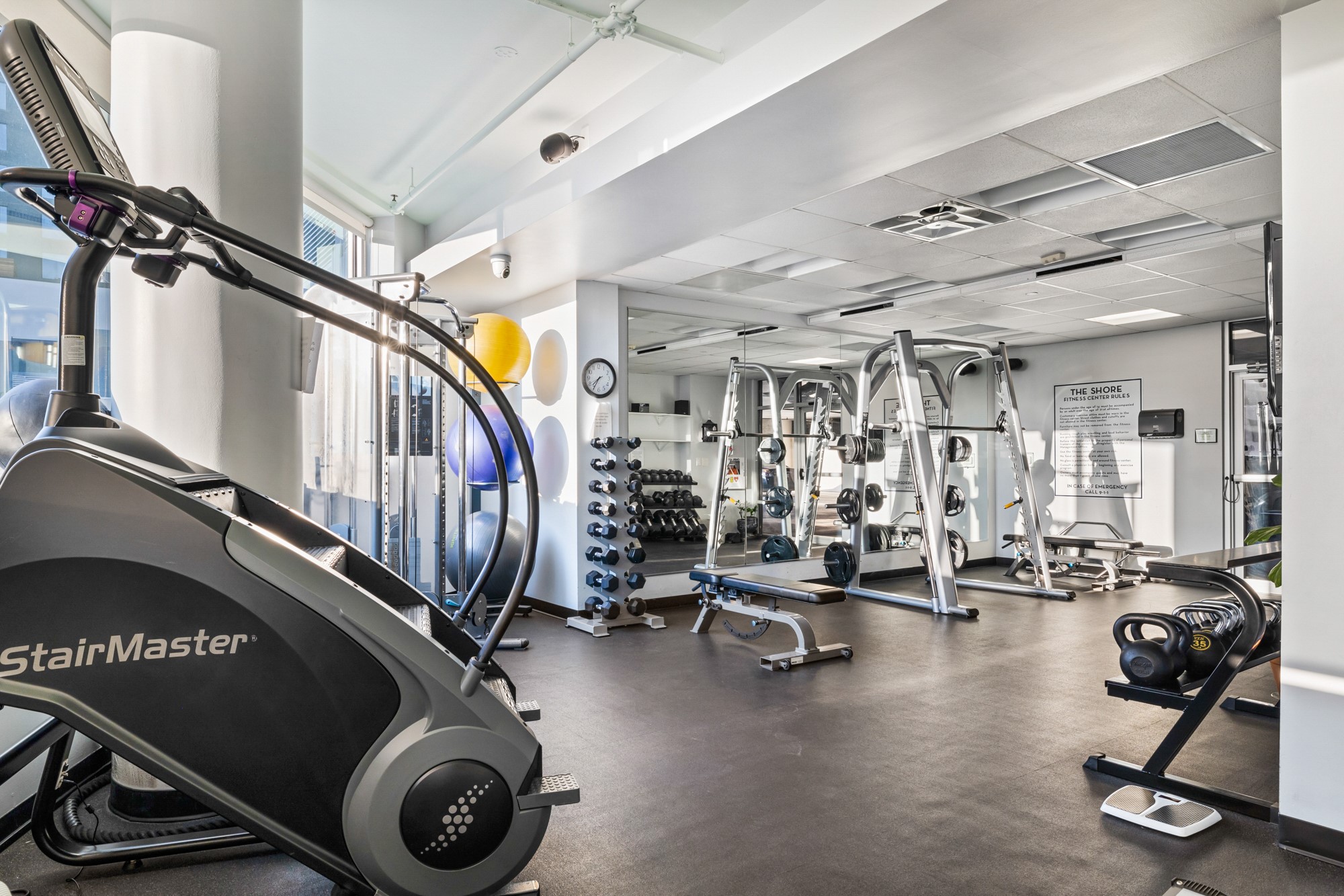 603 Davis Street, Unit 907 Austin, TX 78701 - Photo 18 of 22 Sunlit fitness center featuring wall-to-wall mirrors, rubber flooring, and a full mix of equipment—free weights, a Smith machine, cable station, and cardio—plus a convenient water station for easy workouts at home.