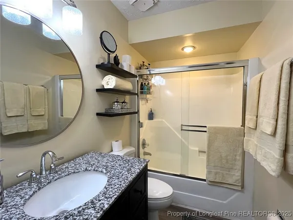 a bathroom with a granite countertop sink mirror vanity and toilet