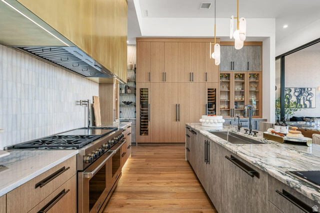 2867 East Granite Way St. George, UT 84790 - Photo 10 of 69 Gourmet kitchen featuring a commercial-grade range, brass hood, natural wood-finish cabinetry, stone countertops, and integrated wine refrigerators