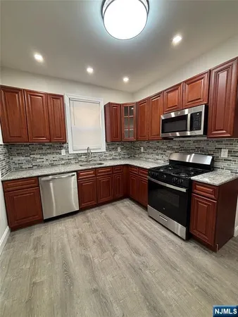 a kitchen with stainless steel appliances granite countertop wooden cabinets a stove a sink and a microwave