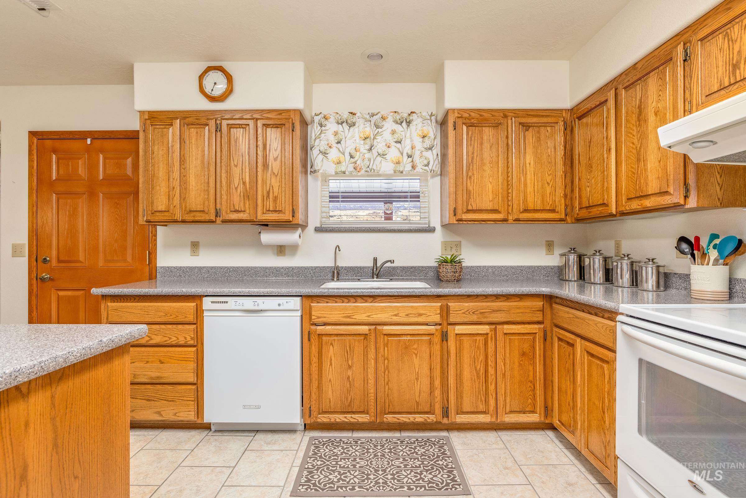 10514 Airpark Loop Road Melba, ID 83641 - Photo 22 of 47 Kitchen featuring white appliances, wood finish cabinets, and light tile patterned floors