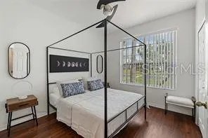 a bedroom with a bed a table and wooden floor