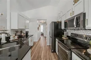 a kitchen with stainless steel appliances a sink dishwasher a refrigerator a stove top oven a wooden floor and cabinets