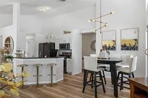 a kitchen with stainless steel appliances kitchen island granite countertop a table chairs and a refrigerator