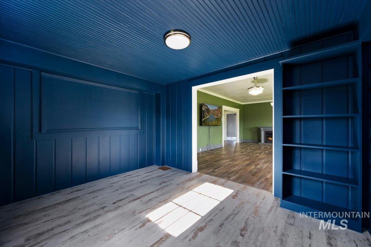 813 7th Street Rupert, ID 83350 - Photo 12 of 48 Room featuring beadboard ceiling, painted board and batten walls, built-in shelving, and wood-finish flooring