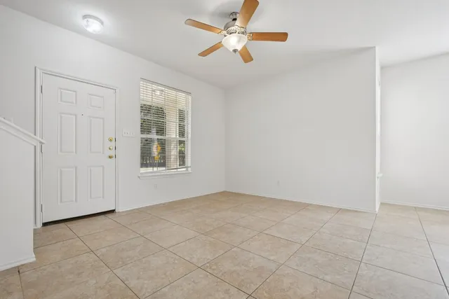 an empty room with a kitchen and a chandelier fan