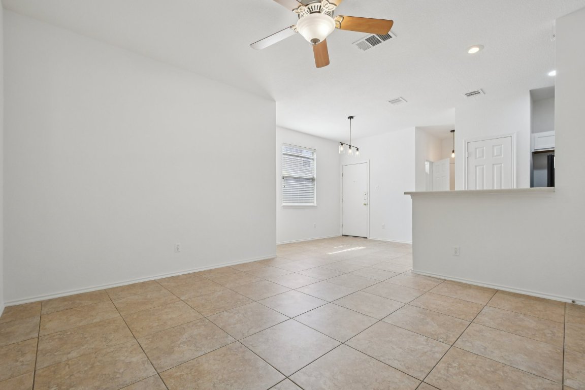 14504 Harris Ridge Boulevard, Unit A Pflugerville, TX 78660 - Photo 9 of 23 an empty room with a kitchen and a chandelier fan