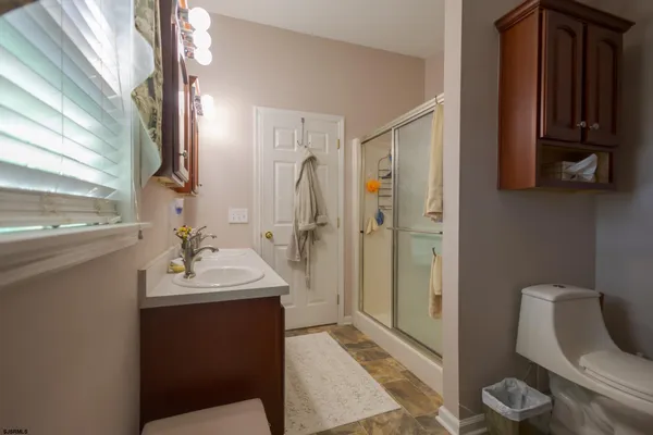 a view of a hallway with wooden floor and a bathroom