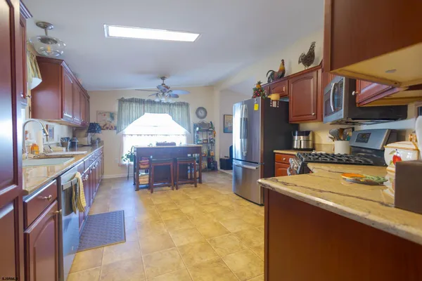 a living room with stainless steel appliances kitchen island granite countertop a table chairs in it and a wooden floor