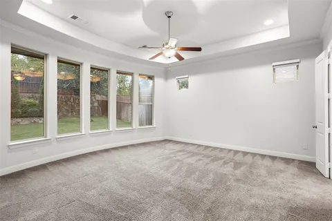 an empty room with windows and ceiling fan