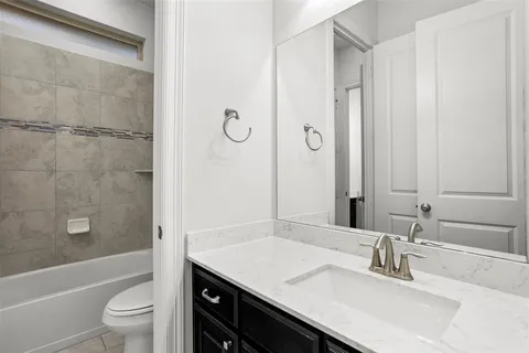 a bathroom with a granite countertop sink a toilet and shower