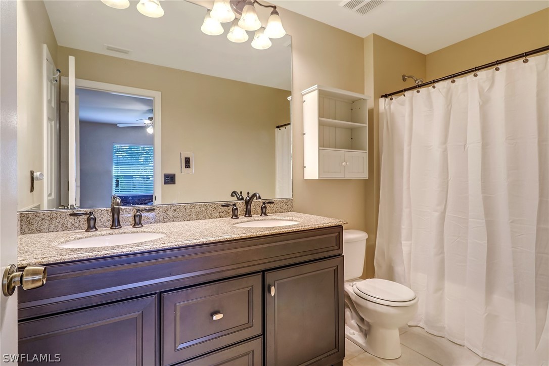 9050 Henry Road Fort Myers, FL 33967 - Photo 11 of 16 a bathroom with a granite countertop sink a toilet and a mirror
