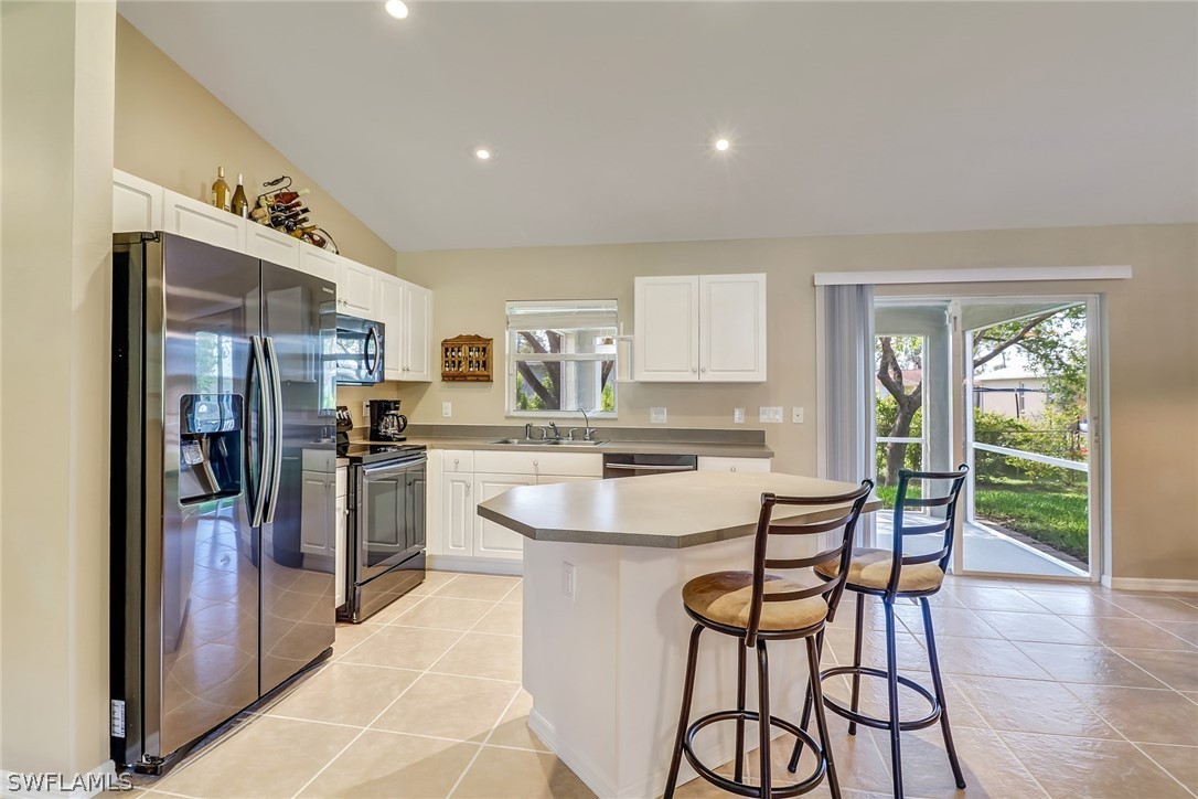 9050 Henry Road Fort Myers, FL 33967 - Photo 7 of 16 a kitchen with stainless steel appliances a refrigerator a stove a sink and white cabinets with wooden floor