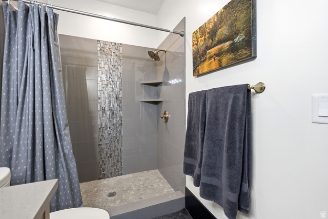 71 Farm Road Midway, UT 84049 - Photo 64 of 92 Walk-in shower featuring gray tile walls, a decorative mosaic tile accent strip, and a pebble-style floor