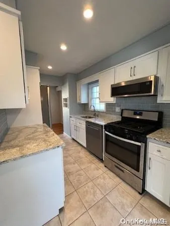 a kitchen with stainless steel appliances granite countertop a stove a sink and a microwave