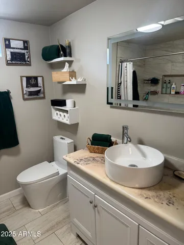 a bathroom with a granite countertop toilet sink and mirror