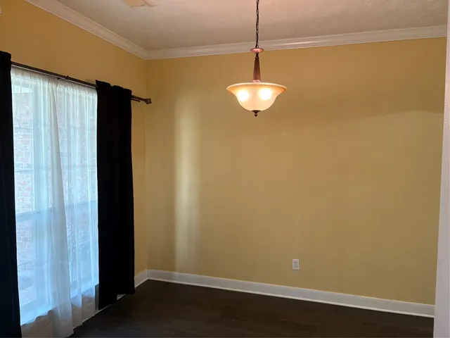 a view of empty room with wooden floor and chandelier