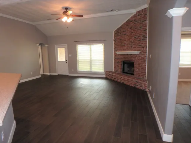 an empty room with wooden floor fireplace and windows