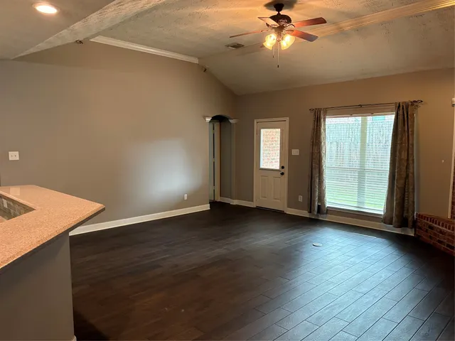 a view of an empty room with window and wooden floor