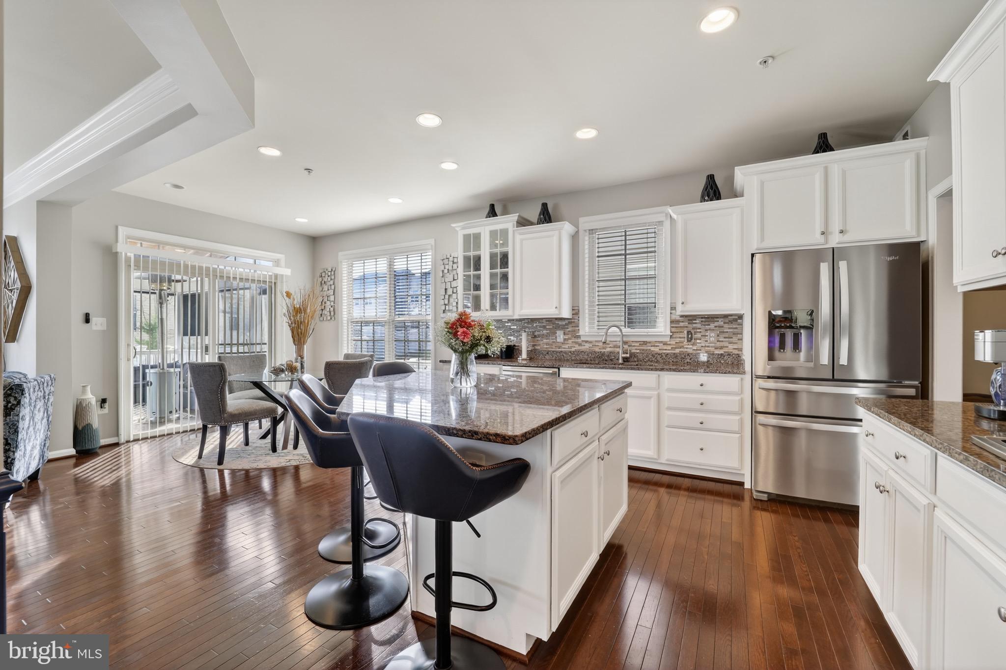 9205 Rice Avenue Lanham, MD 20706 - Photo 16 of 68 a kitchen with stainless steel appliances granite countertop a refrigerator a stove a sink a dining table and chairs with wooden floor