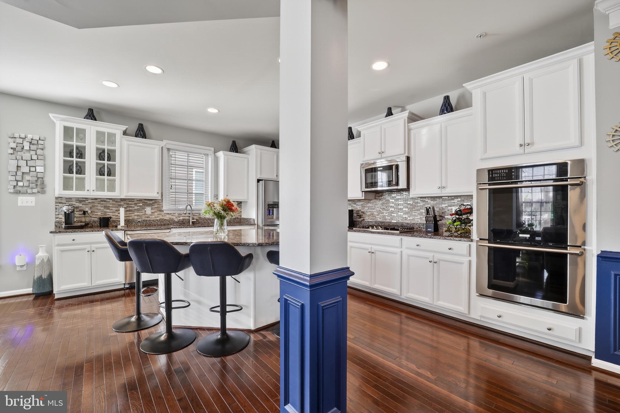 9205 Rice Avenue Lanham, MD 20706 - Photo 18 of 68 a kitchen with stainless steel appliances kitchen island granite countertop a stove a sink a refrigerator and white cabinets with wooden floor