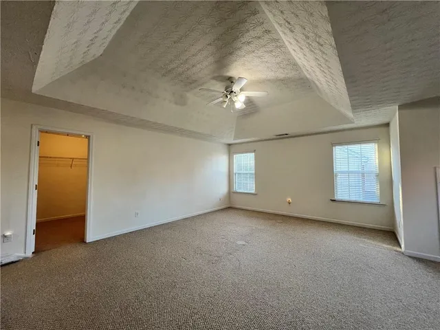 an empty room with a ceiling fan and windows