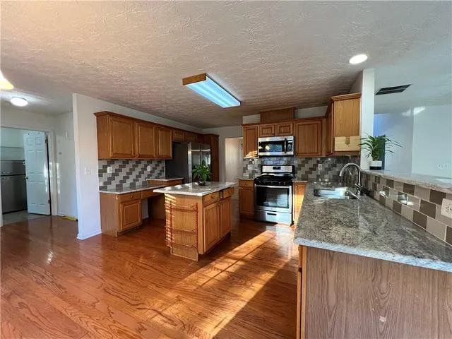 a kitchen with stainless steel appliances kitchen island granite countertop a stove a sink and a refrigerator