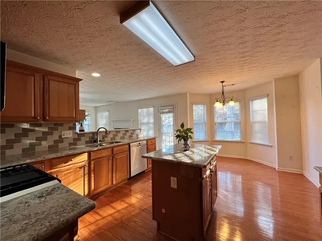 a kitchen with stainless steel appliances granite countertop a sink stove and wooden cabinets