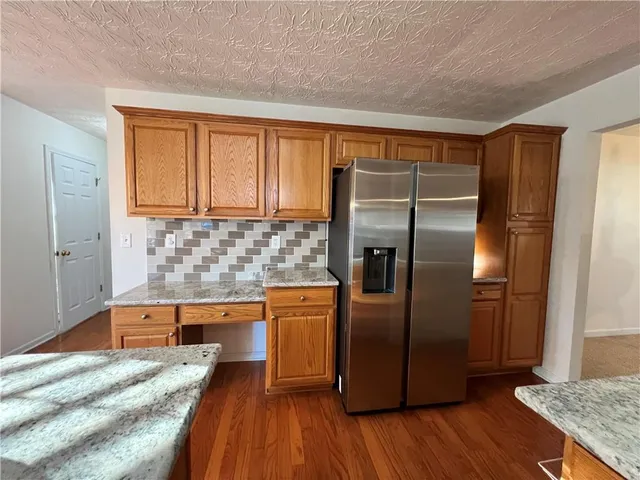 a kitchen with stainless steel appliances granite countertop a refrigerator a sink and wooden cabinets