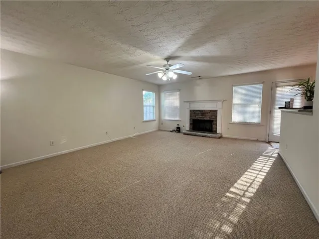 an empty room with windows and fireplace