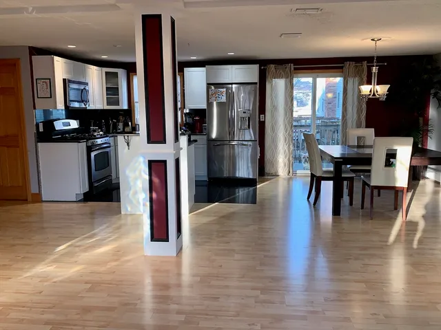 an open kitchen with refrigerator and wooden floor