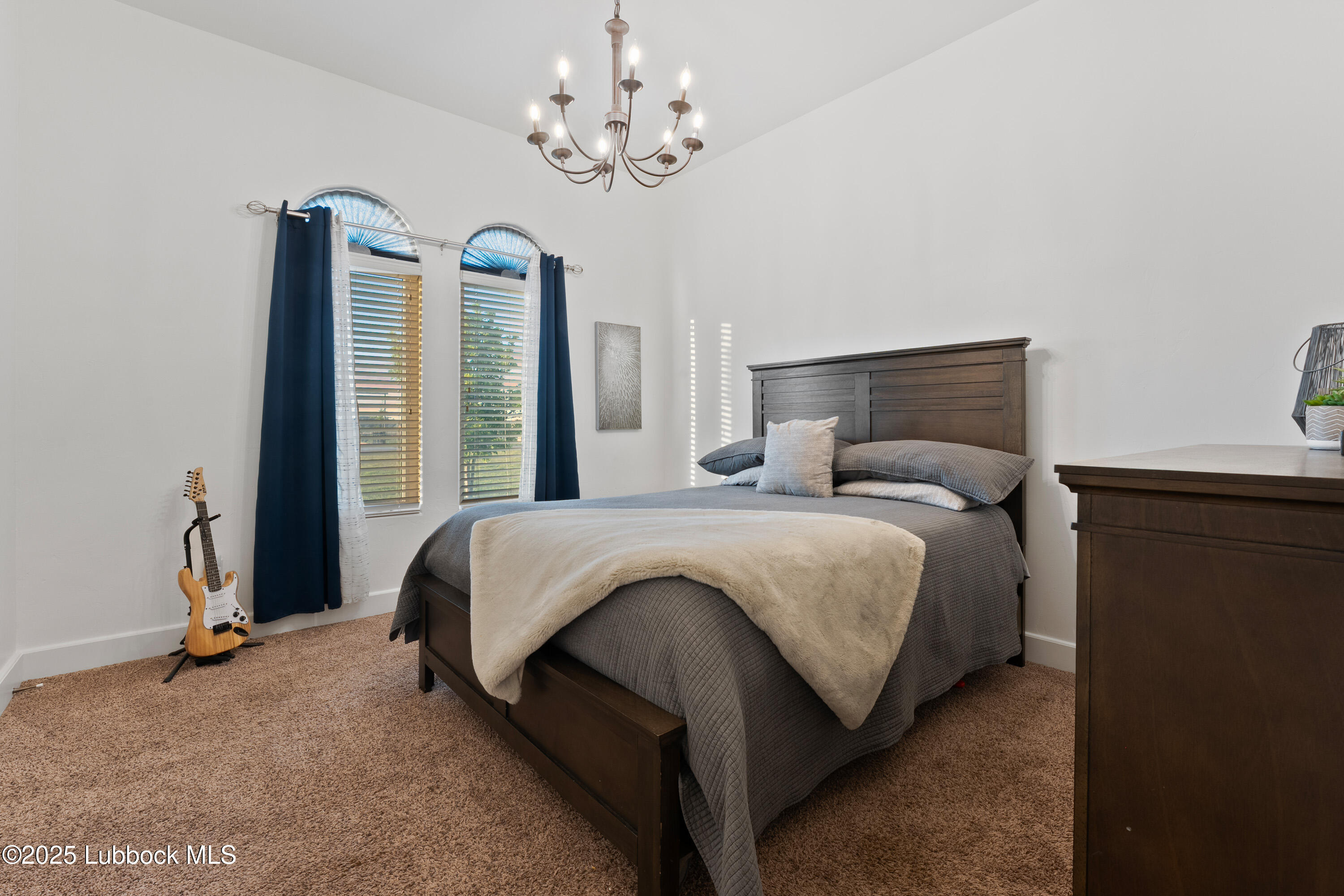 5125 County Road 7930 Lubbock, TX 79424 - Photo 33 of 75 a bedroom with a large bed and a chandelier