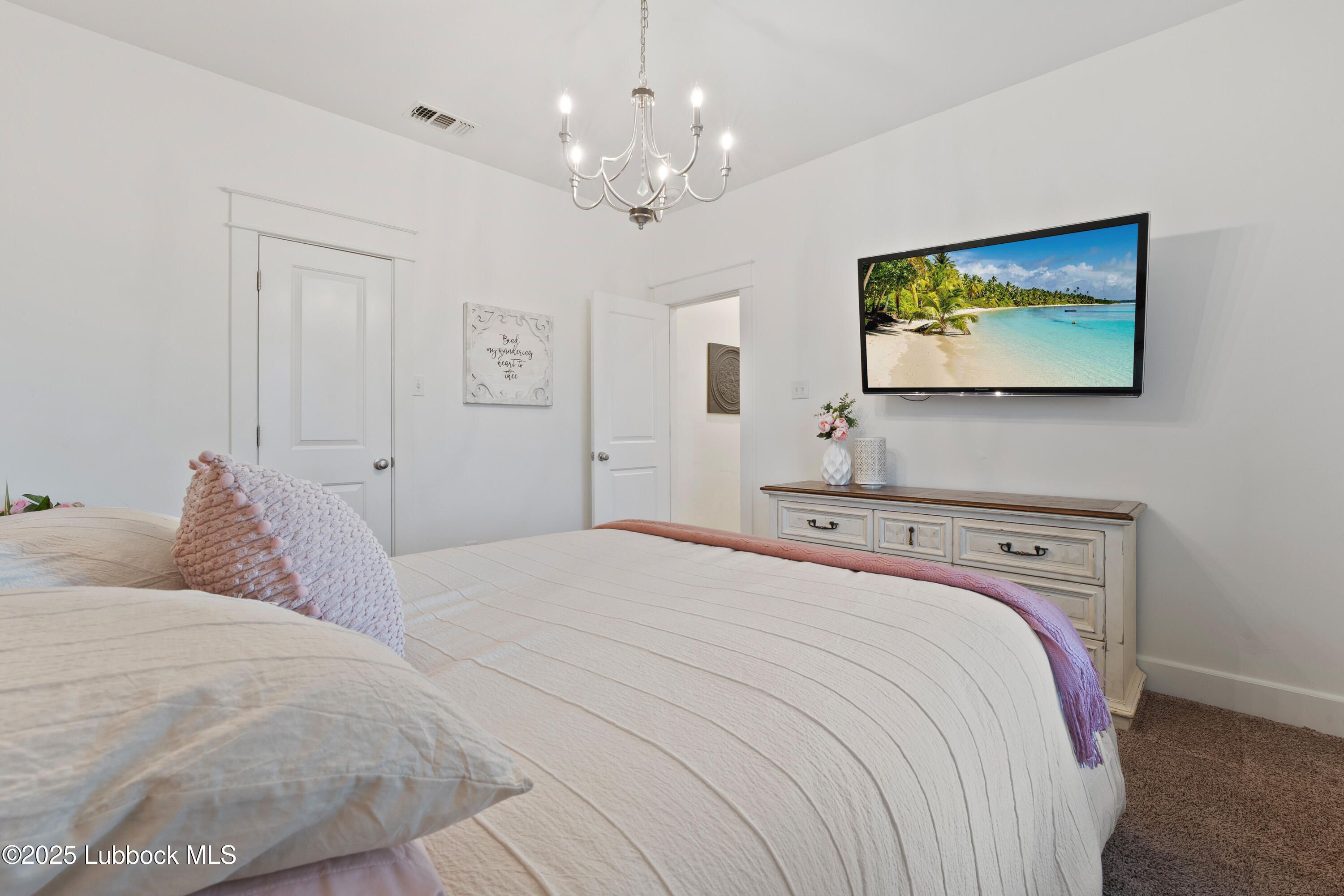 5125 County Road 7930 Lubbock, TX 79424 - Photo 36 of 75 a bedroom with a large bed and a chandelier