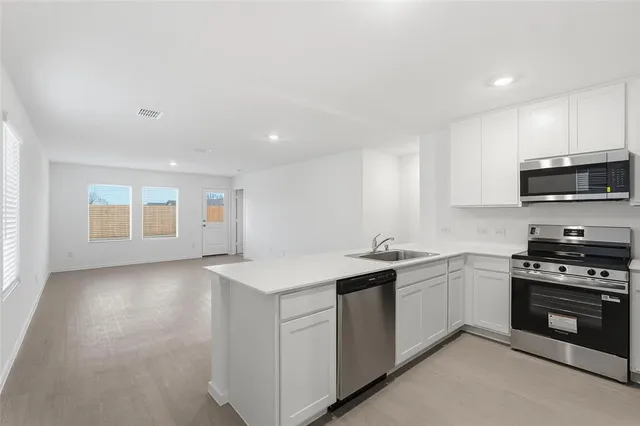 a kitchen with stainless steel appliances granite countertop a sink stove and microwave