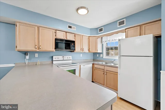 a kitchen with granite countertop a refrigerator stove top oven a sink and dishwasher