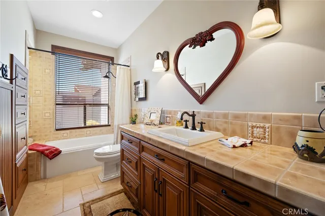 a bathroom with a granite countertop sink a toilet a mirror and bathtub