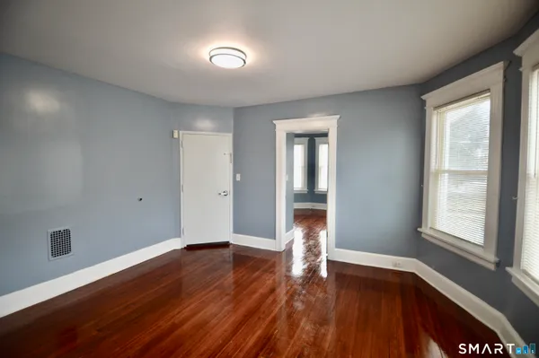a view of an empty room with wooden floor and a window