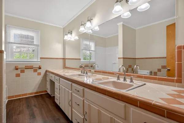 a bathroom with double vanity sink a vanity and a large mirror