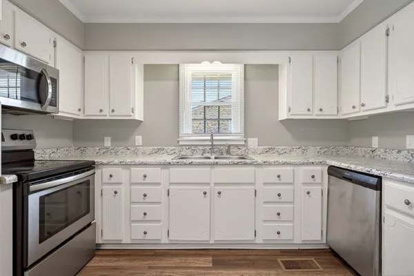 a kitchen with granite countertop white cabinets and stainless steel appliances