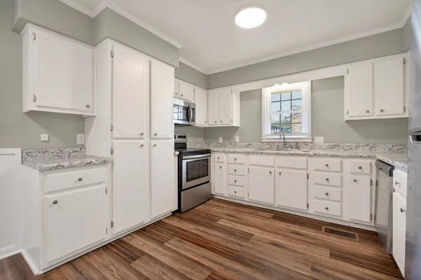 a kitchen with granite countertop white cabinets white appliances a sink and a window