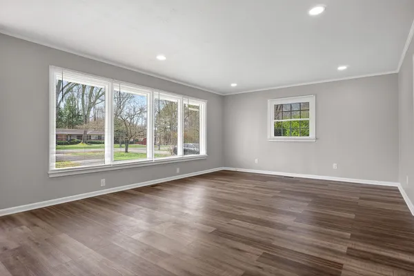 a view of an empty room with wooden floor and a window