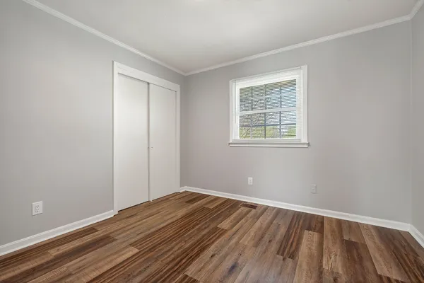 a view of an empty room with wooden floor and a window