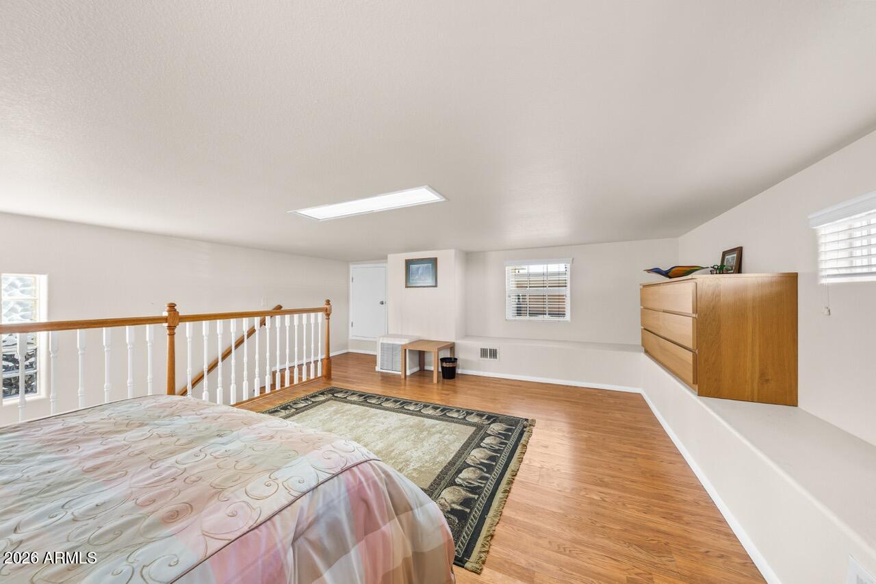 17200 West Bell Road, Unit 1784 Surprise, AZ 85374 - Photo 15 of 25 a bedroom with a large bed and a wooden floor