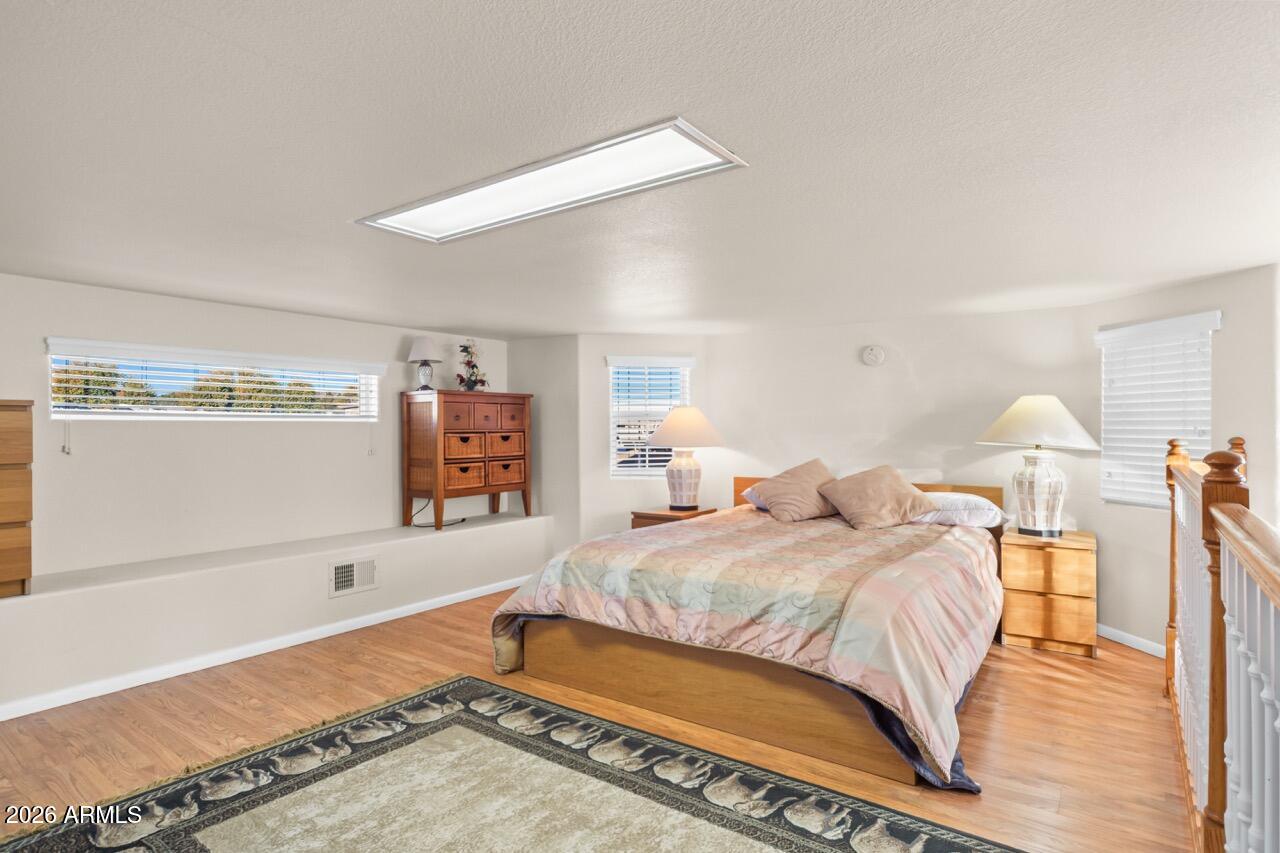 17200 West Bell Road, Unit 1784 Surprise, AZ 85374 - Photo 4 of 25 a bedroom with a bed and a walk in closet with wooden floor